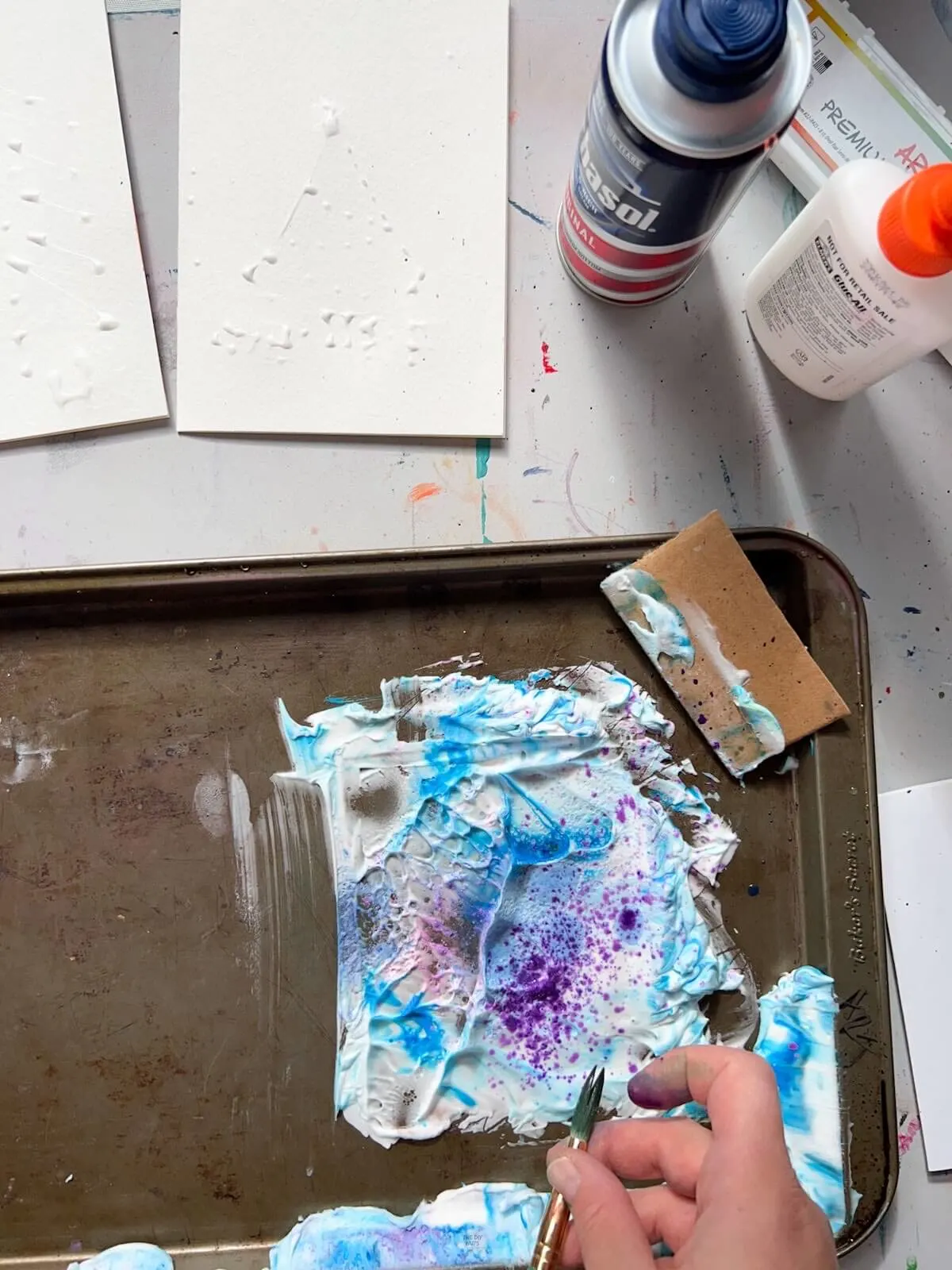 finger spraying watercolor paint on shaving cream.