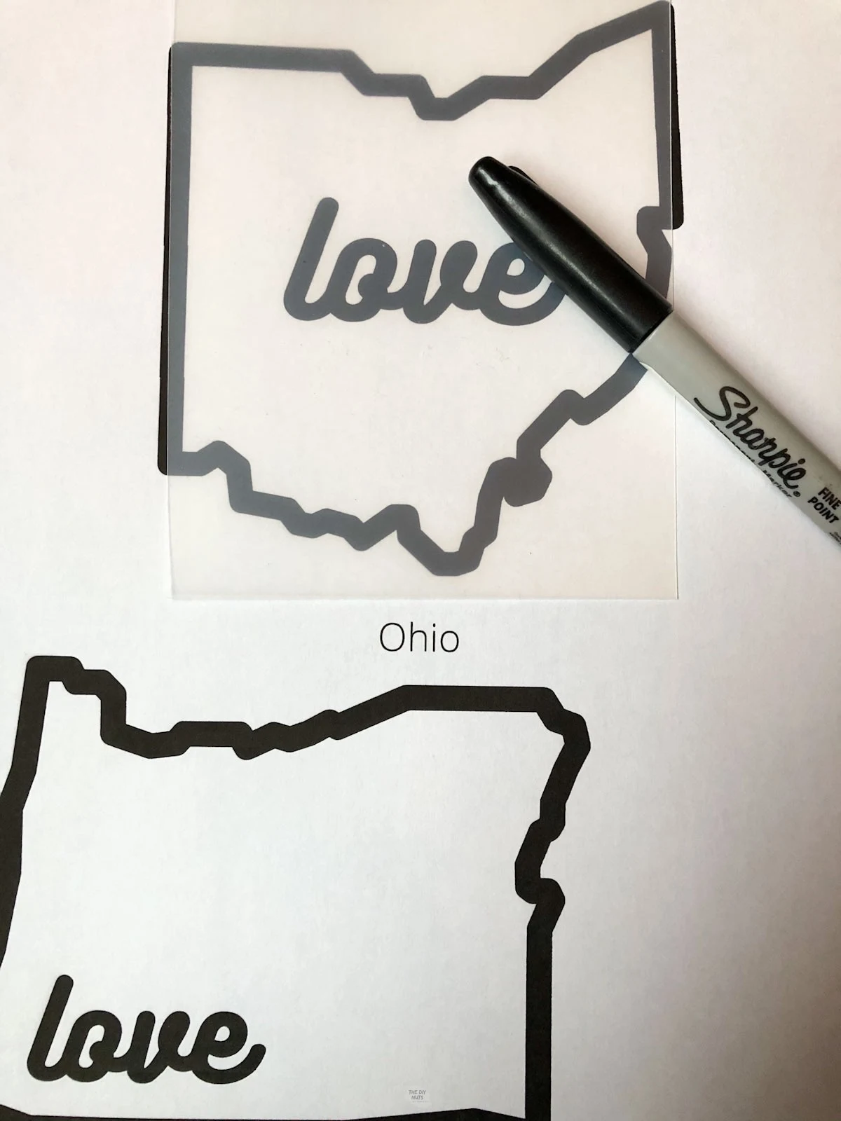 plastic Shrinky Dink film on top of outline of Ohio with love spelled inside and black sharpie.