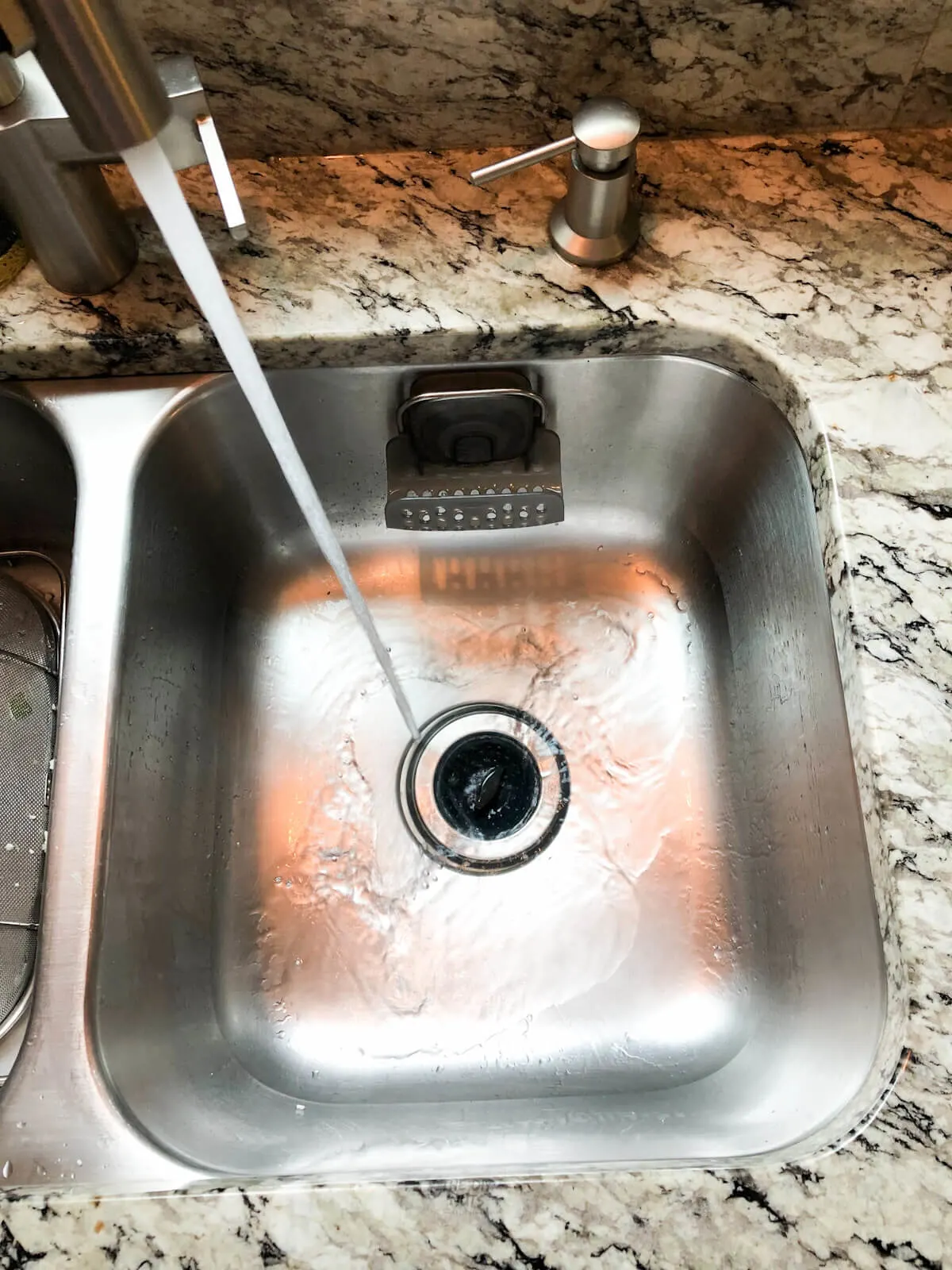stainless steel sink being filled with water